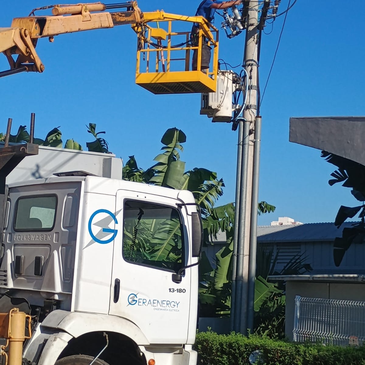 Caminhão munck da frota própria da Geraenergy com a cesta elevada e técnico trabalhando no poste